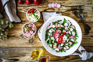 Fresh salad - feta cheese, radish and leafy greens on wooden table
