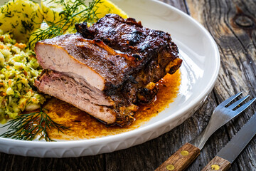 Tasty roast ribs with boiled potatoes and coleslaw on wooden table
