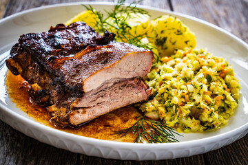 Tasty roast ribs with boiled potatoes and coleslaw on wooden table
