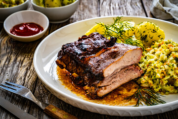 Tasty roast ribs with boiled potatoes and coleslaw on wooden table
