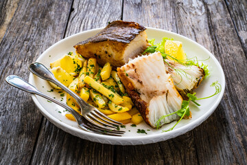 Fish dish - fried halibut with French fries and lemon on wooden table
