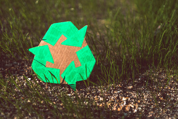 recycle sign hand drawn on cardboard over green grass