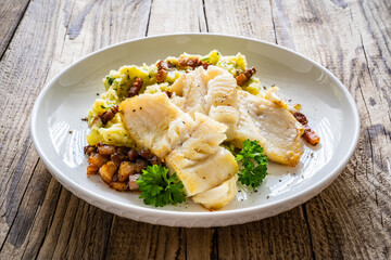 Fish dish - fried cod fillet with potato puree and bacon on wooden table
