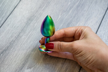woman hand holding bright shiny butt anal plug