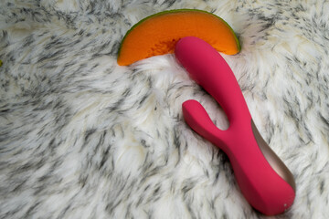 vibrator sex toy rabbit with fruits on gray fur background, concept of pleasure, sex shop advertisement 