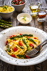 Pasta with asparagus, parmesan and tomatoes on wooden table
