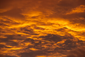 Swirling evening clouds illuminated by the setting sun - obrazy, fototapety, plakaty