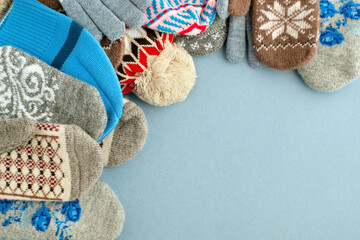 Hats, mittens and gloves on a blue background. Clothing in the form of hats, mittens, gloves. Knitted clothes for autumn and winter.