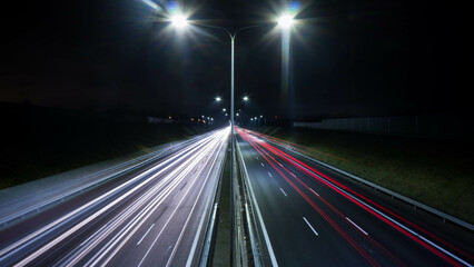 night view of the highway, visible flares of street lamps, streaks of car lights