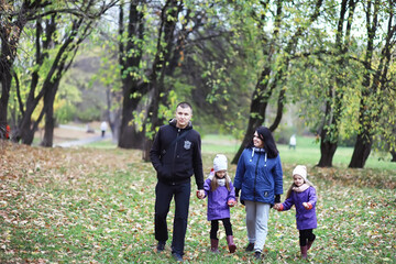 Naklejka na ściany i meble Leaf fall in the park. Children for a walk in the autumn park. Family. Fall. Happiness.