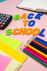 Back to school letters, with school supplies on top of a pink table.