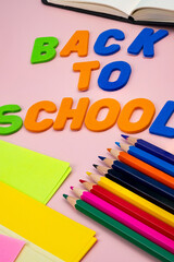 Back to school letters, with school supplies on top of a pink table.