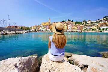 Vacation relax. Girl sitting on stone enjoying landscape of French Riviera on sunny day, Menton, France. - obrazy, fototapety, plakaty