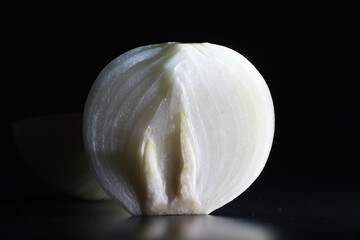 Fresh onion bulbs on black background. Bulb onion is rich in vitamins, useful spring. Onion peel on a dark background. Raw sliced onions.