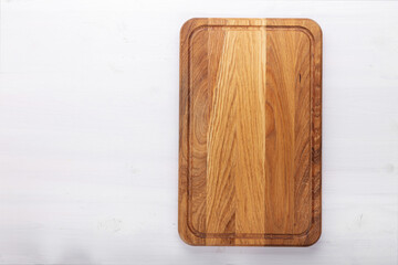 Rectangular cutting board on a white wooden table. Food preparation tool and kitchen utensils.