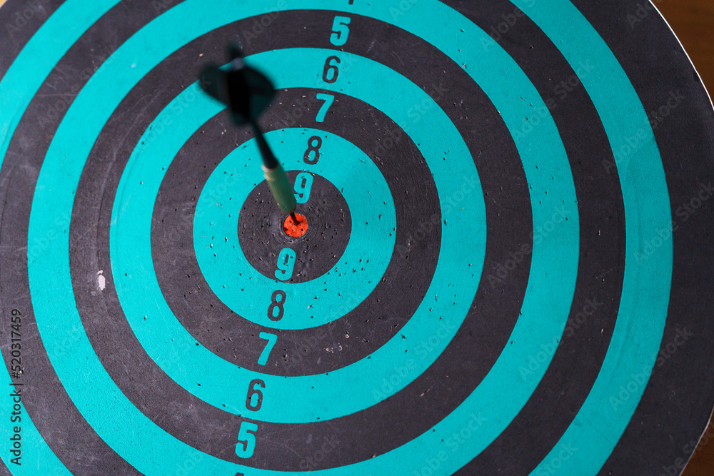 Poster close up shot of the dart arrow hit on bulleyes of dartboard to represent that the business reached 
