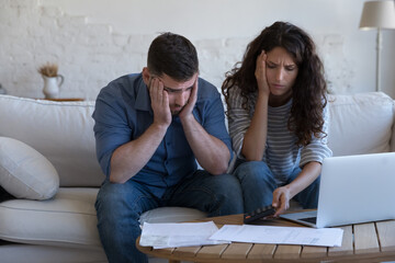 Concerned upset millennial couple counting overspent budget, doing paperwork, thinking on financial...