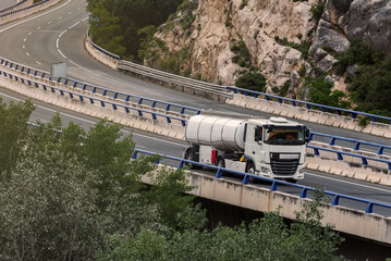 Small single-axle tanker truck driving on the highway.