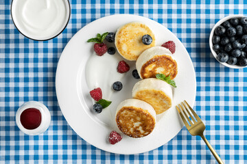 Cottage cheese pancakes on the background is blue in a cell. Syrniki with fresh blueberries.  Homemade food. Recipe. Copy space for text