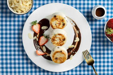 Cottage cheese pancakes (curd fritters or syrniki) with fresh berries and chocolate sauce on white...