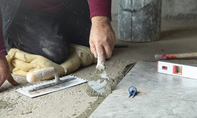 Worker using spatula and putting glue on floor.