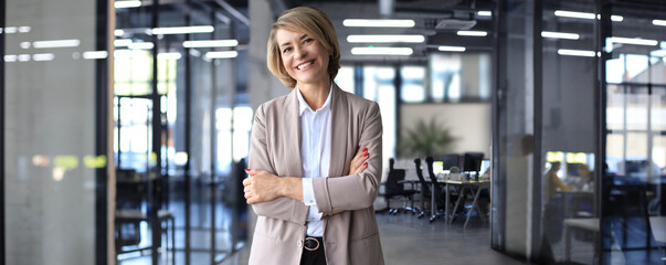 Confident stylish european middle aged woman standing at workplace, executive leader manager...