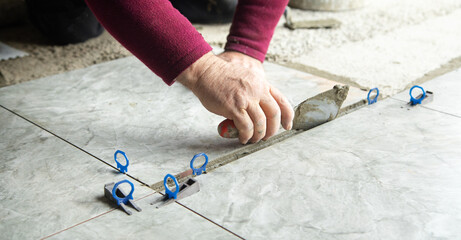 Worker using spatula and putting glue on floor.