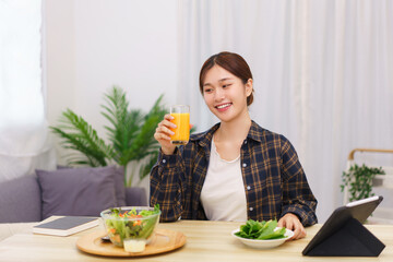 Lifestyle in living room concept, Asian woman drinking orange juice and eating vegetable salad
