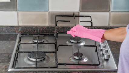 A woman's hand holds the grate from the gas stove for cleaning