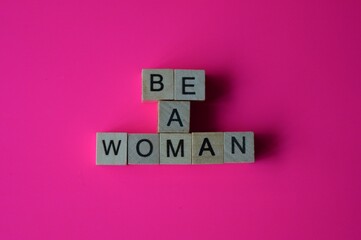 The inscription be a woman written with small wooden blocks with letters on a pink background