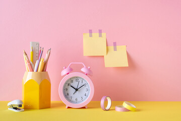 School supplies concept. Photo of stationery pink alarm clock adhesive tape stand for pens stapler...