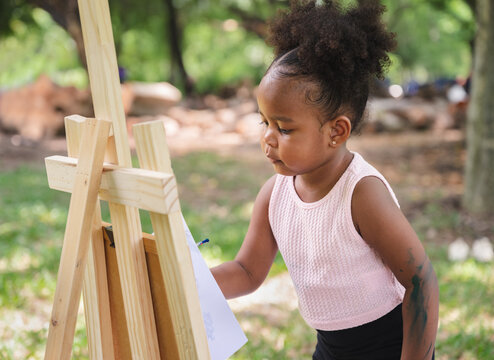 African American kid girl painting in the park