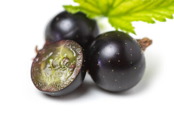 Group of black currants with leaves, one sliced in half