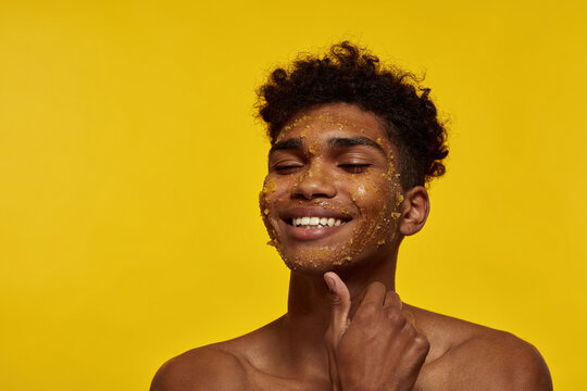 Smiling guy with honey scrub on his face skin