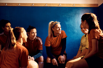 Soccer player and her teammates discuss tactics in dressing room.