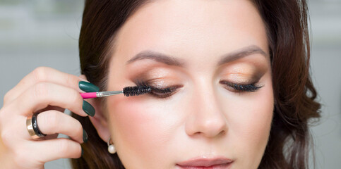 The stylist paints the client's eyelashes. Makeup.
