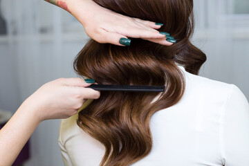 A beautiful girl does styling in a beauty salon. Hollywood curls. Hairstyle