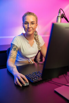 Portrait of Blonde Gamer Girl with Glasses Playing Online Video Game on Her Computer