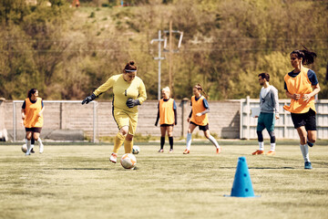 Soccer goalie practicing with ball on sports training at stadium.