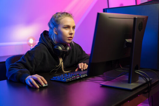 Focused Professional E-sport Gamer Girl in Hoody Playing Online Video Game on PC