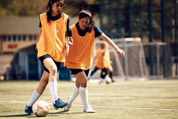 Female players playing with ball during soccer training at stadium.