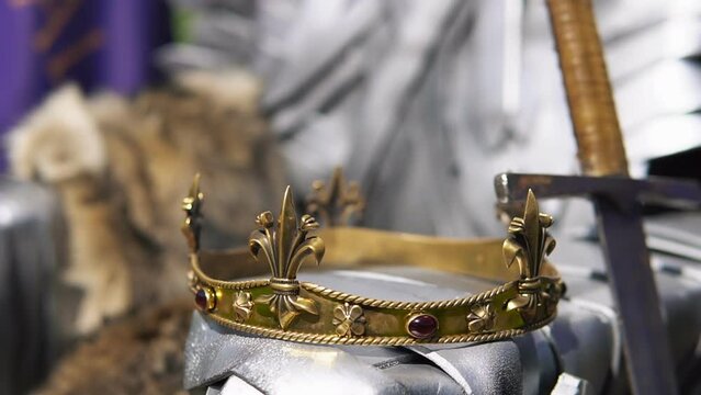Golden king crown and sword on the throne. Medieval period concept. Close up.