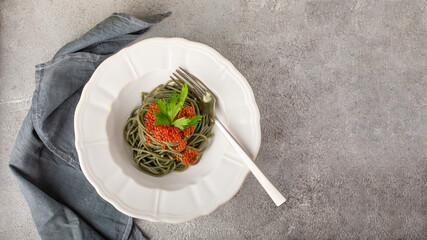 Spirulina noodles with red caviar on a white plate top view