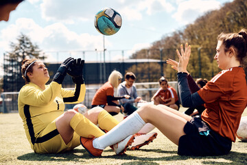 Soccer goalie and her teammate doing sit ups while passing ball to each other during sports...