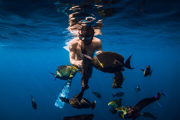 Freediver man with diving mask and school of tropical fish in sea
