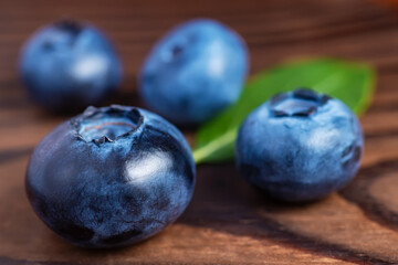 Fresh blueberries with leaves on wooden background