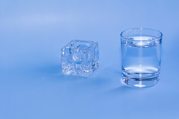 A full glass with clean clear water and an empty container for medicines stands on a blue...
