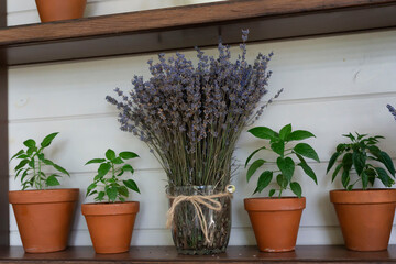 A bouquet of lavender in a pot and other flowers are on the shelves of the rack.