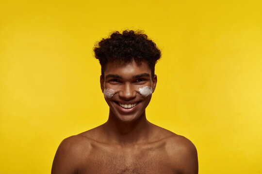 Smiling black guy with cosmetic cream on his face