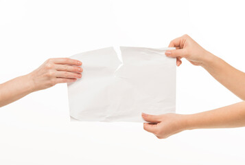 two pairs of female hands hands hold pull in different directions tear a blank sheet of paper...